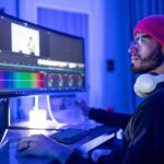 A YouTube editor sitting on a chair in front of a computer, editing videos