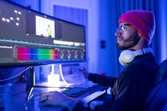 A YouTube editor sitting on a chair in front of a computer, editing videos